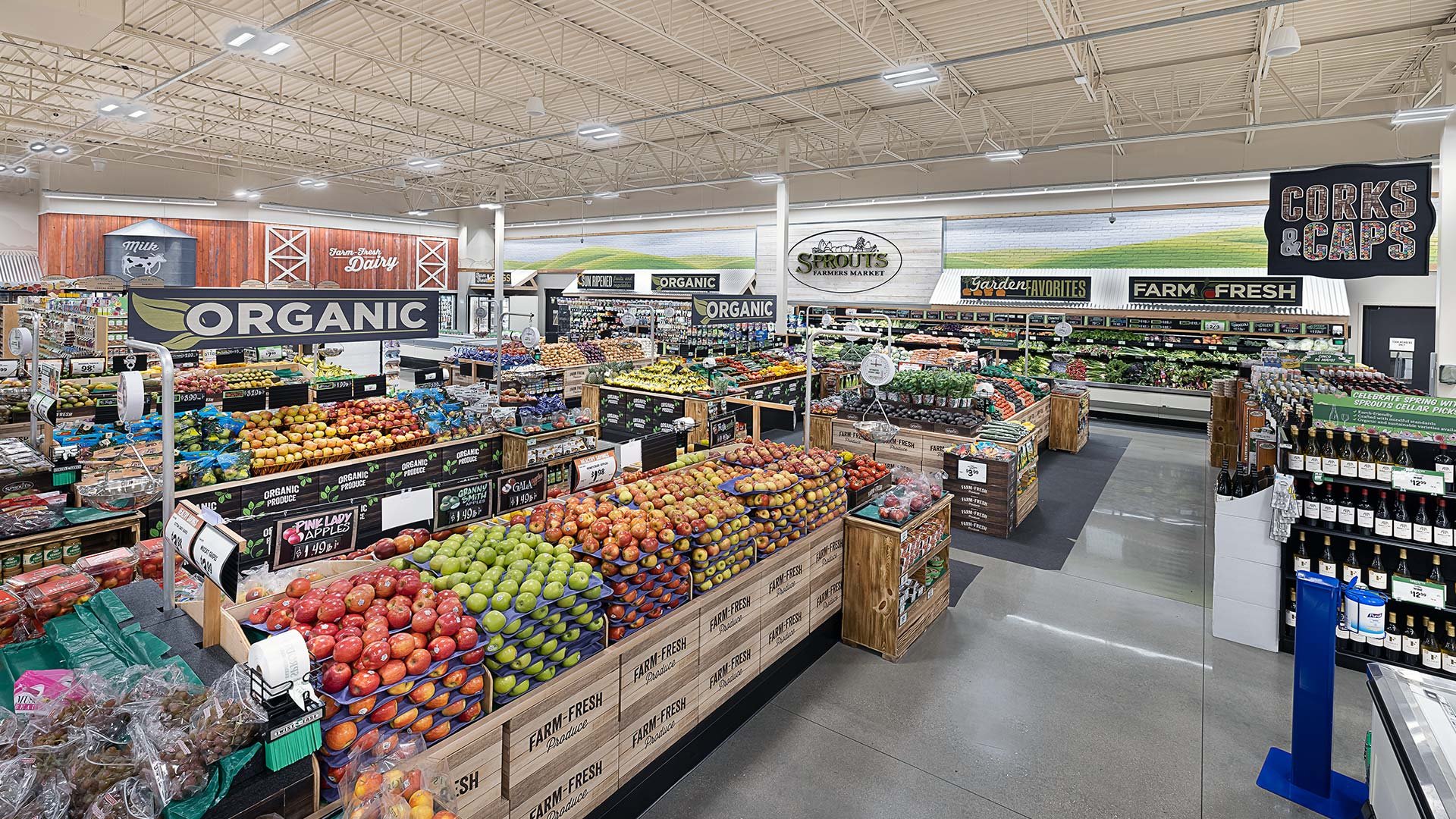 Interior of a grocery store with fresh produce, signs for organic and farm-fresh items, and shelves of fruits, vegetables, and other products.