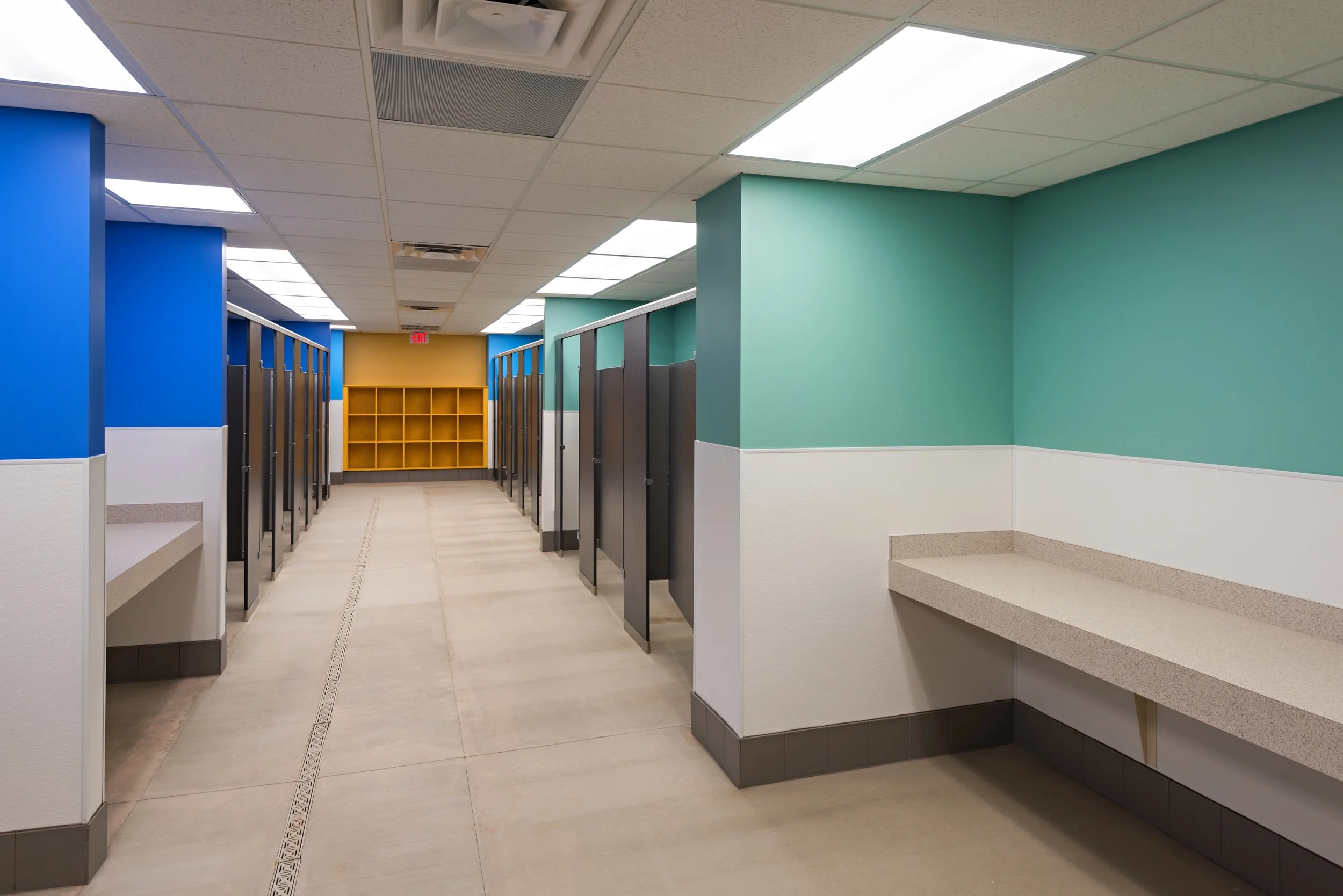 Empty changing room hallway in a public swim or gym facility with colorful walls, lockers, and cubbies.