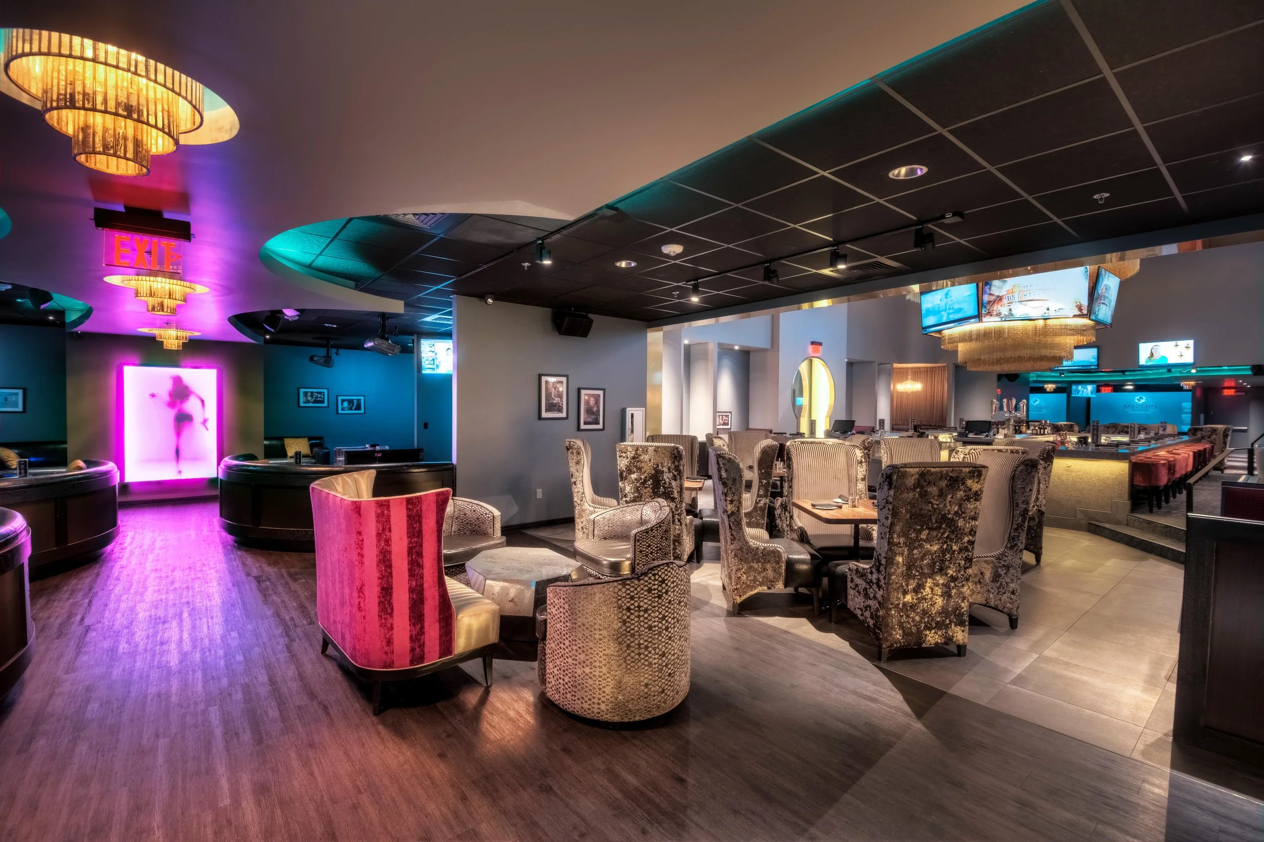 Interior of a modern lounge or bar with various seating options, colorful lighting, a bar area, and decorative elements