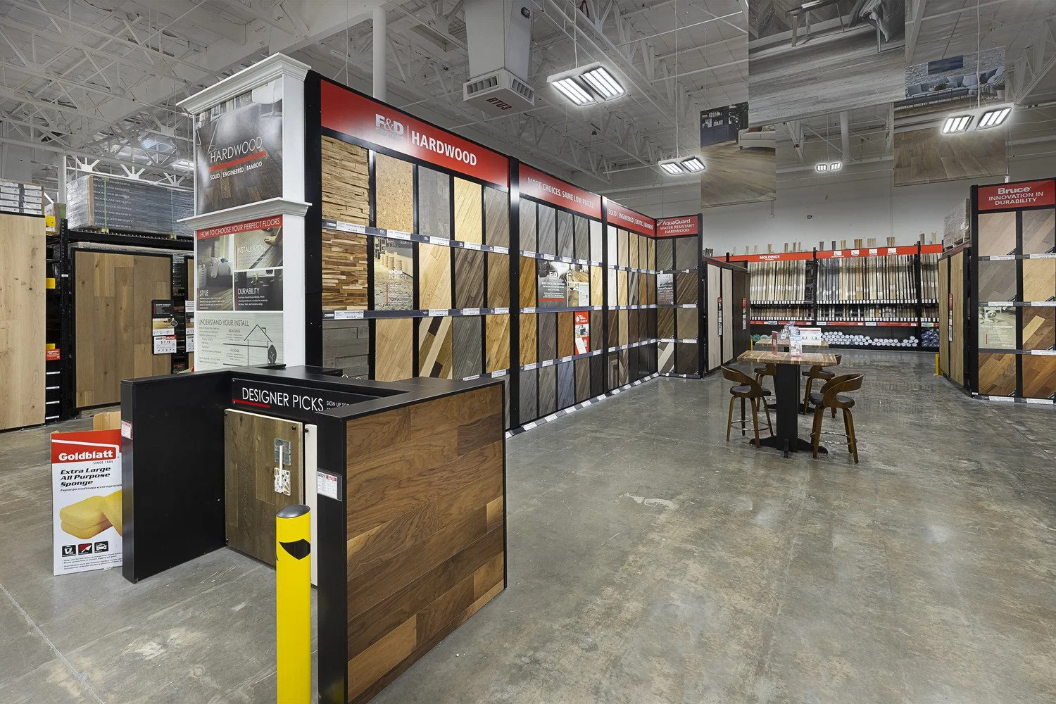Inside a home improvement store, showing displays of hardwood flooring samples and building materials.