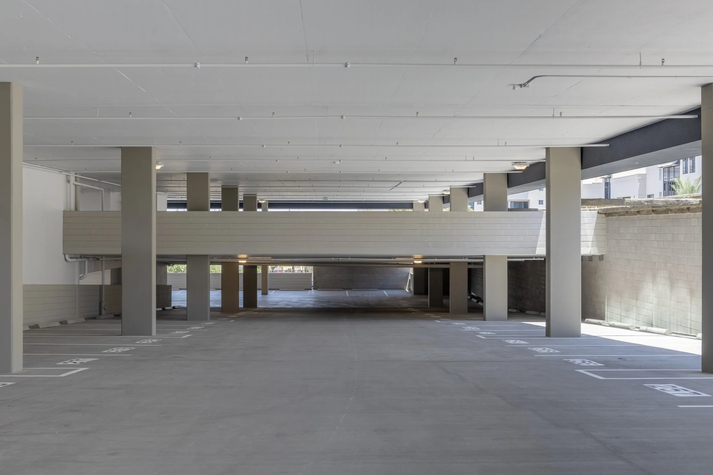 Empty multi-level parking garage with parking spaces and concrete pillars.