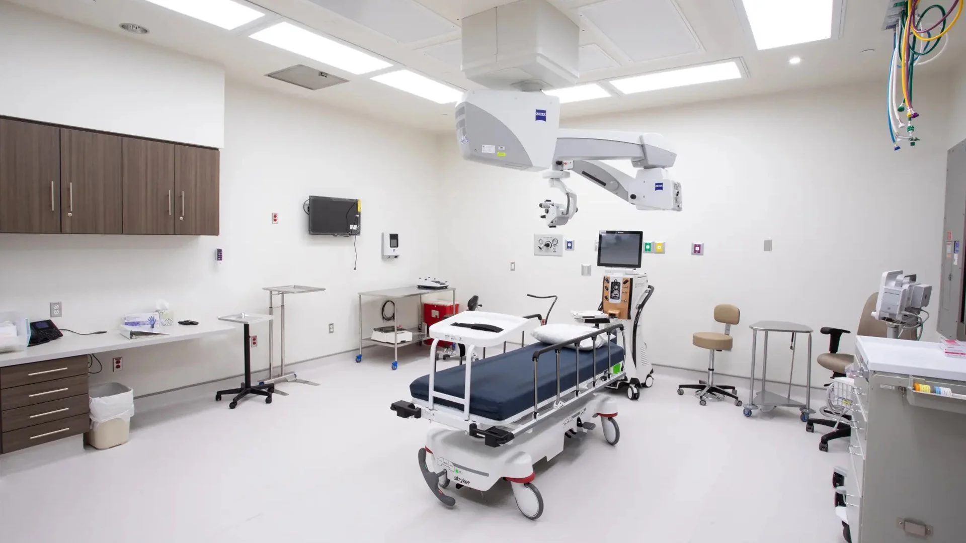 A sterile hospital room with medical equipment, a hospital bed, and a robotic surgical system.