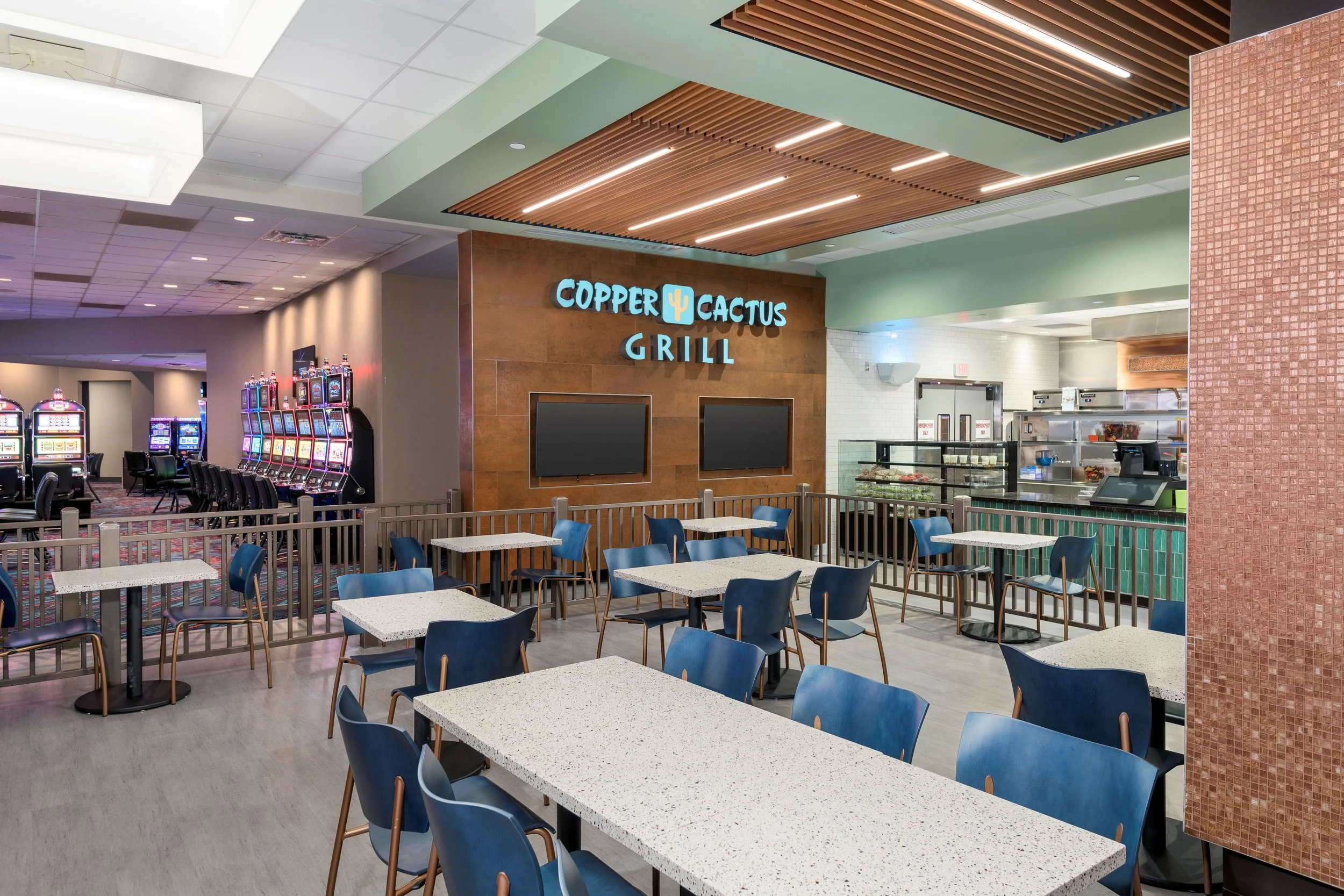 Interior of a restaurant named Copper Cactus Grill with tables, chairs, and a display counter in the background.