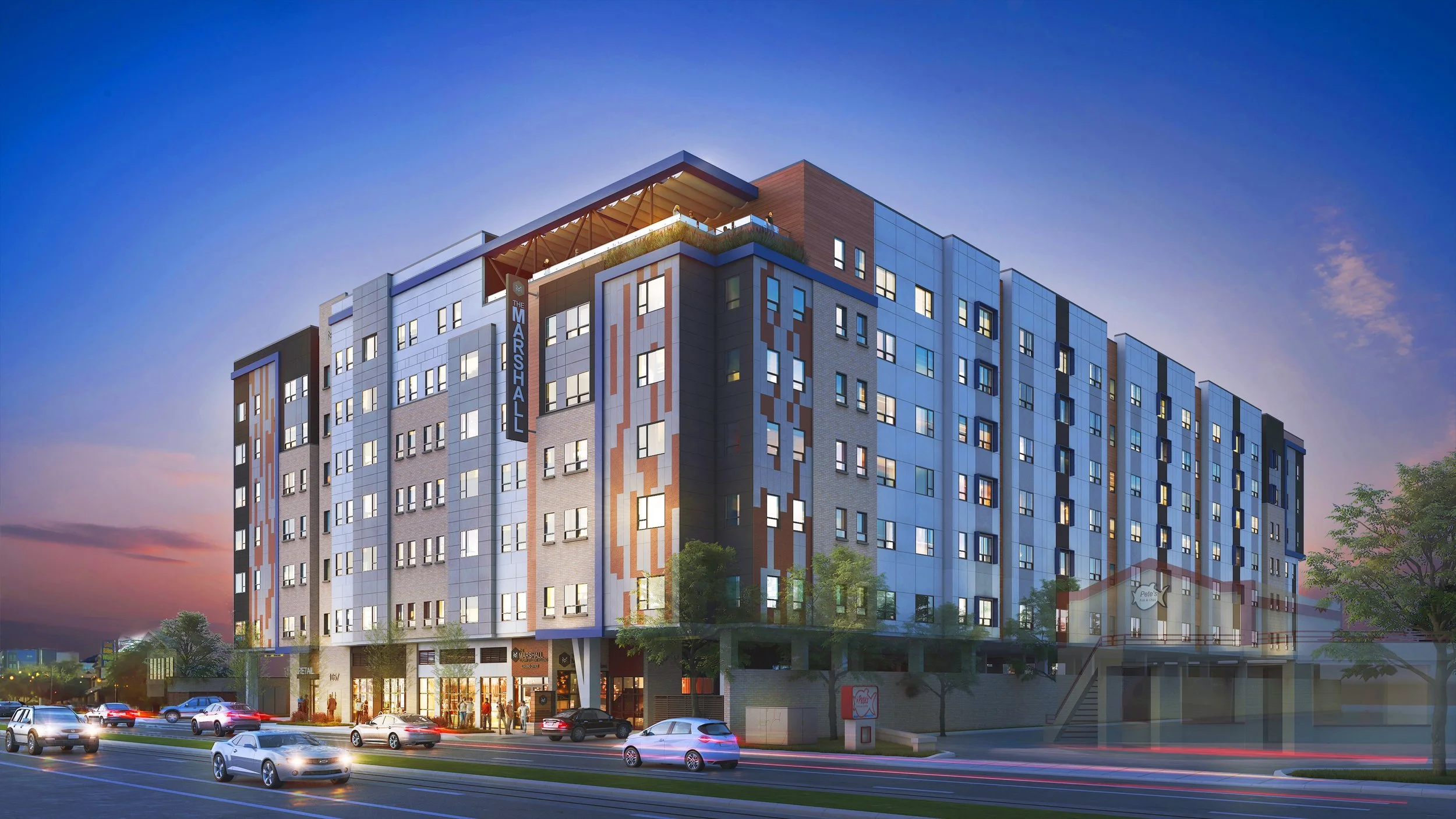 Modern multi-story apartment building with cars on the street at dusk, trees, and a sign for The Marshal.