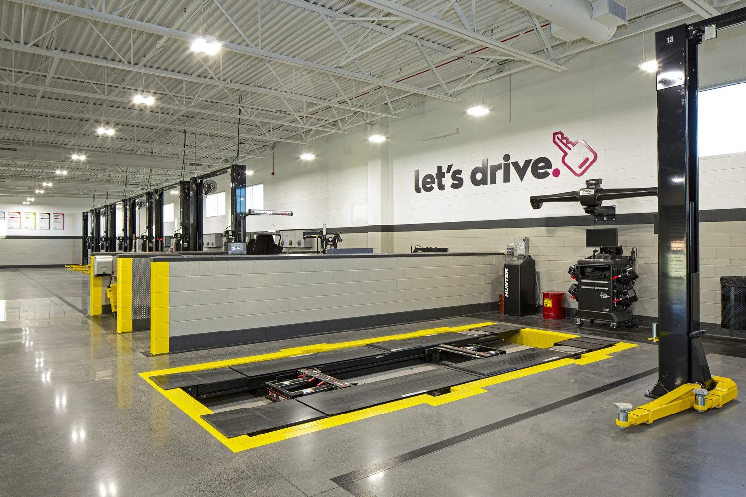 Automotive service center with a vehicle lift, diagnostic equipment, and bay stations, under a sign that reads "let's drive."