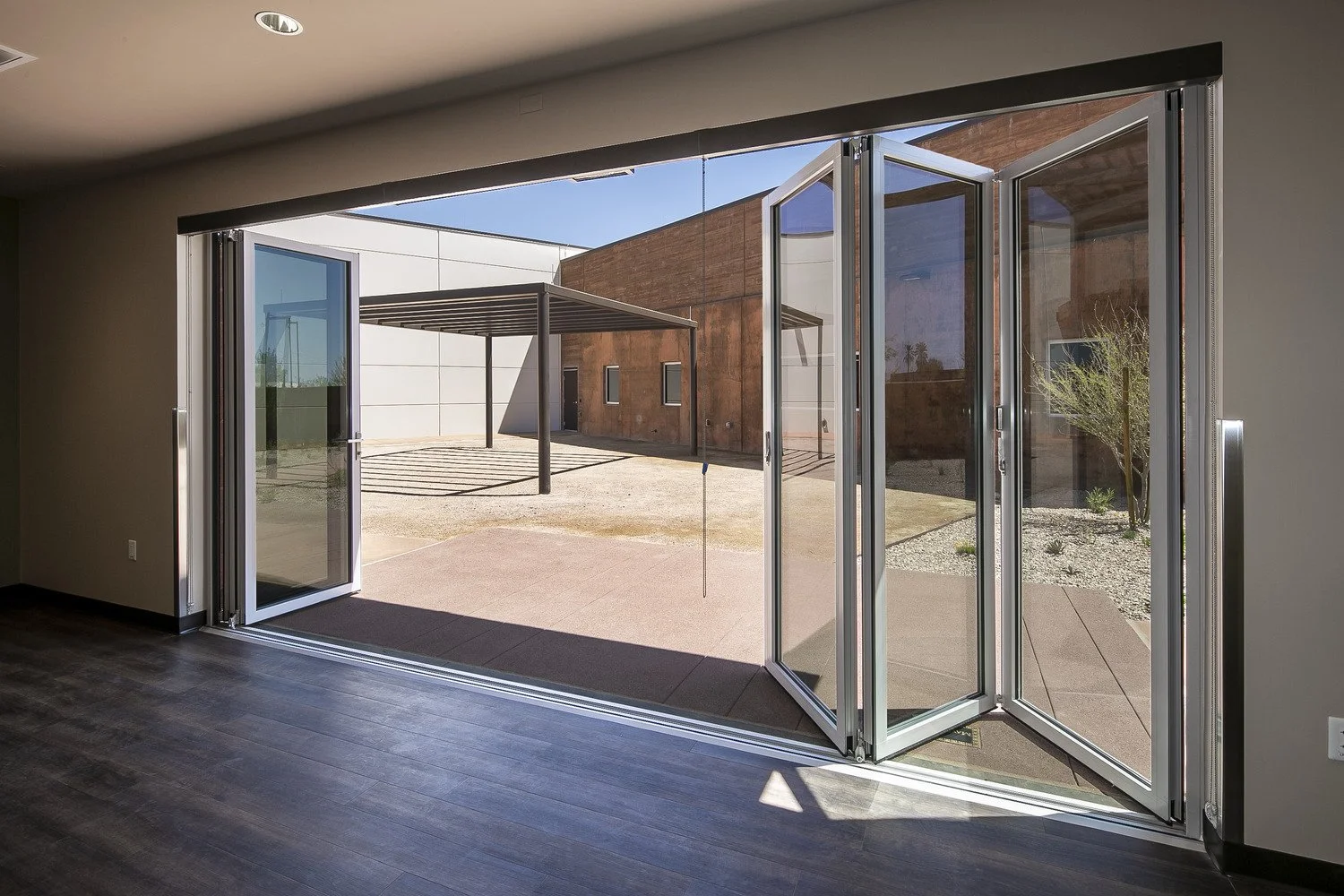 Open glass sliding doors leading to an outdoor patio with a modern building in the background.