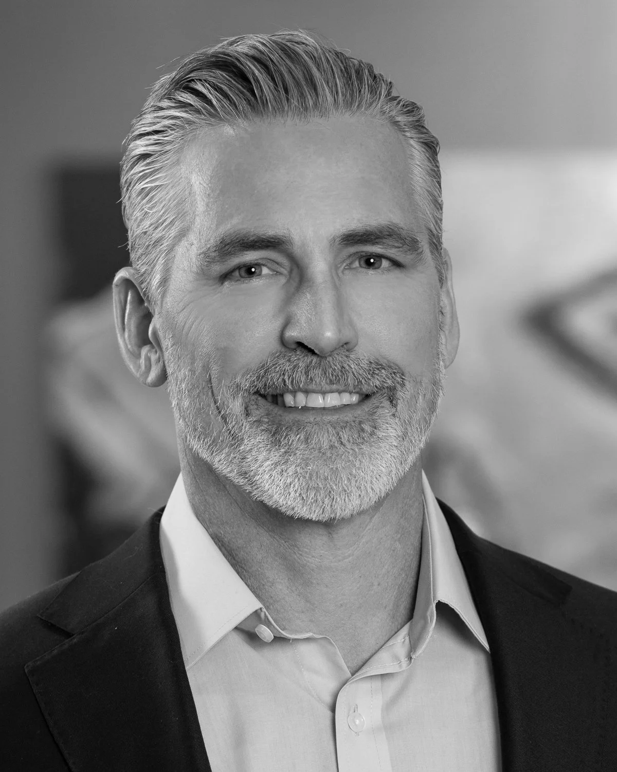Black and white portrait of Joe Barth, Executive Vice President of A.R. Mays Construction, smiling.