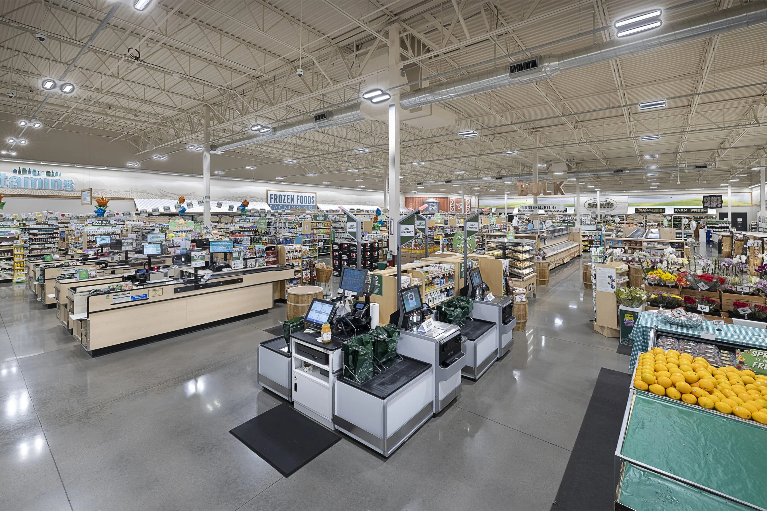 Interior of a supermarket with checkout counters, grocery aisles, and a produce section.