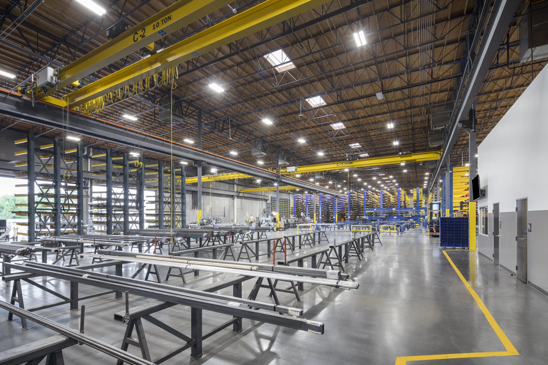 Empty industrial warehouse with workbenches, cranes, and tools for manufacturing.