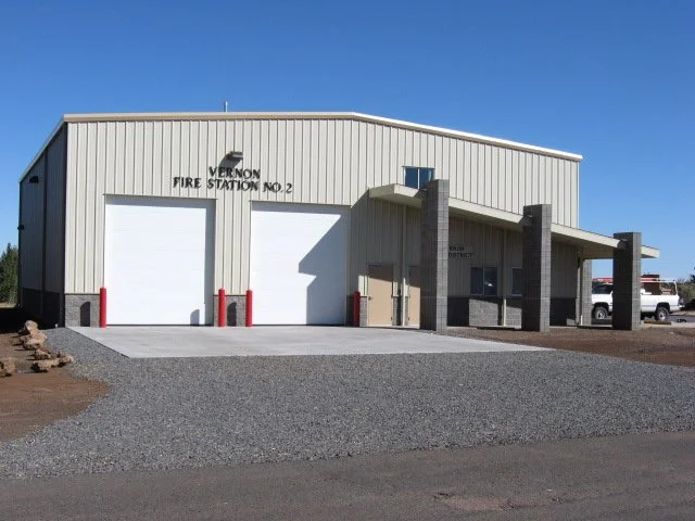Exterior of Vernon Fire Station No. 2 building with garage doors and a small entrance, under a clear blue sky.