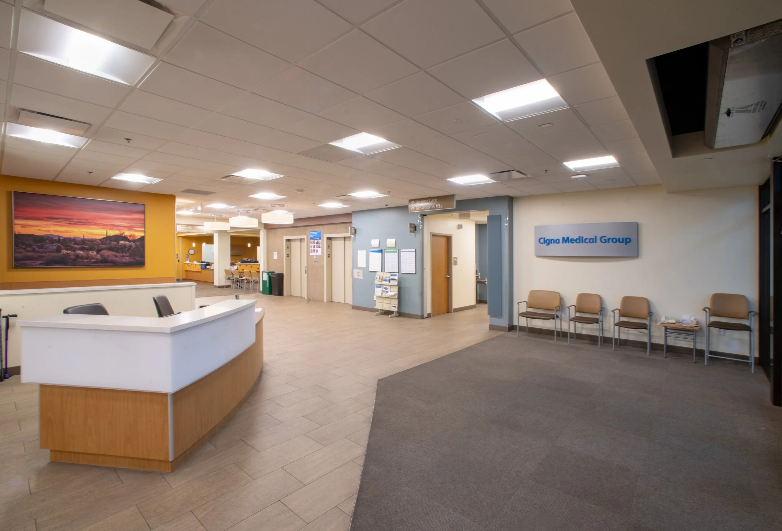 Inside a medical clinic with a reception desk, seating area with chairs, and a sign for Cigna Medical Group.