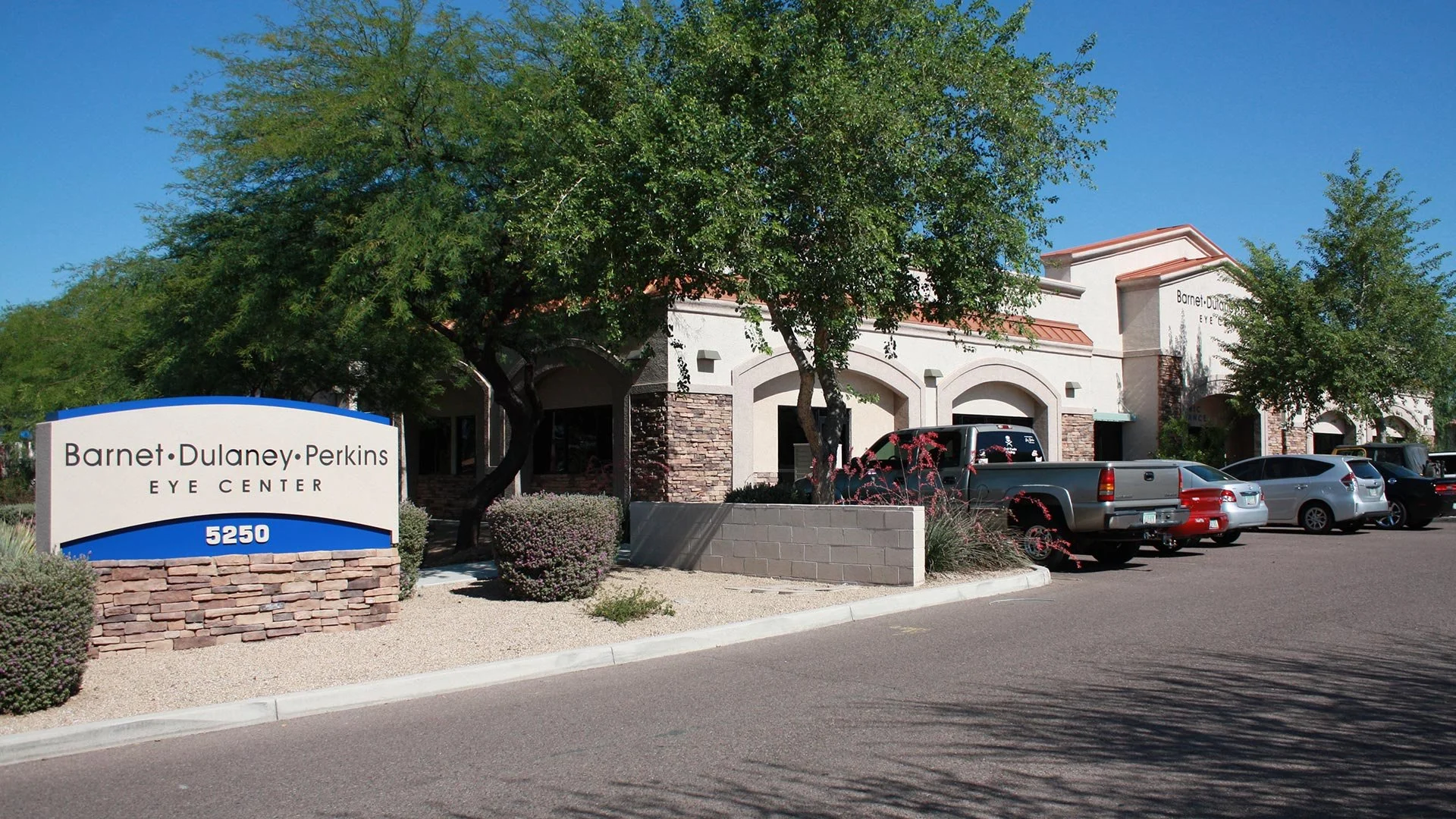 Exterior view of Barnet, Dulaney, Perkins Eye Center building with parking lot and trees, address 5250.
