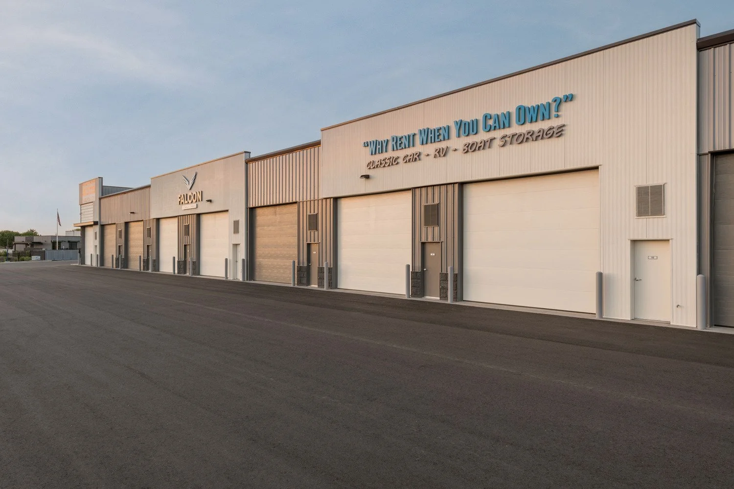 A commercial building with multiple garage doors, a Falcon sign, and blue and black text advertising "Way Rent When You Can Own" for classic cars, RVs, and boat storage.