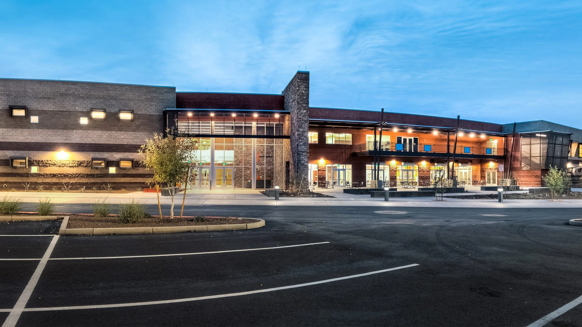 A modern, well-lit commercial building with parking lot at dusk.