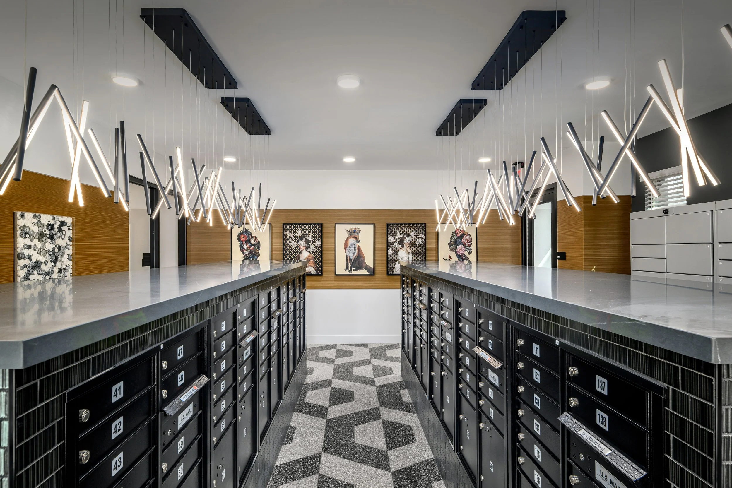 Modern lobby with black mailboxes, artistic lighting fixtures, and contemporary artwork on the walls.
