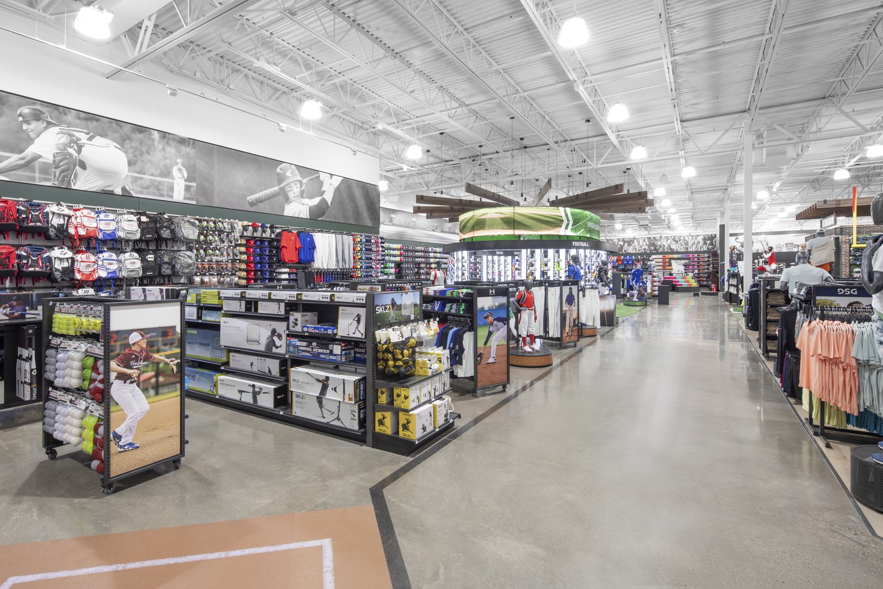 Interior of a sporting goods store with baseball equipment, athletic clothing, and sports memorabilia on display.