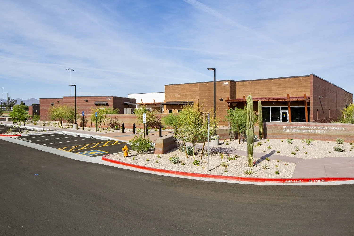 Modern building with desert landscaping, cacti, and parking lot, labeled as Salt River Pima-Maricopa Indian Community Cultural Repository.