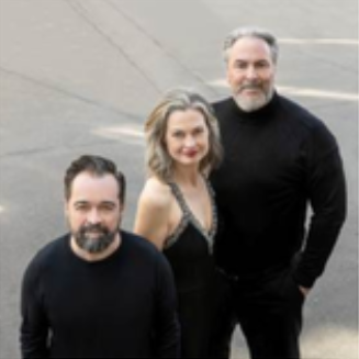 Drei Menschen stehen auf einer Straße und posieren für ein Foto, alle lächeln.