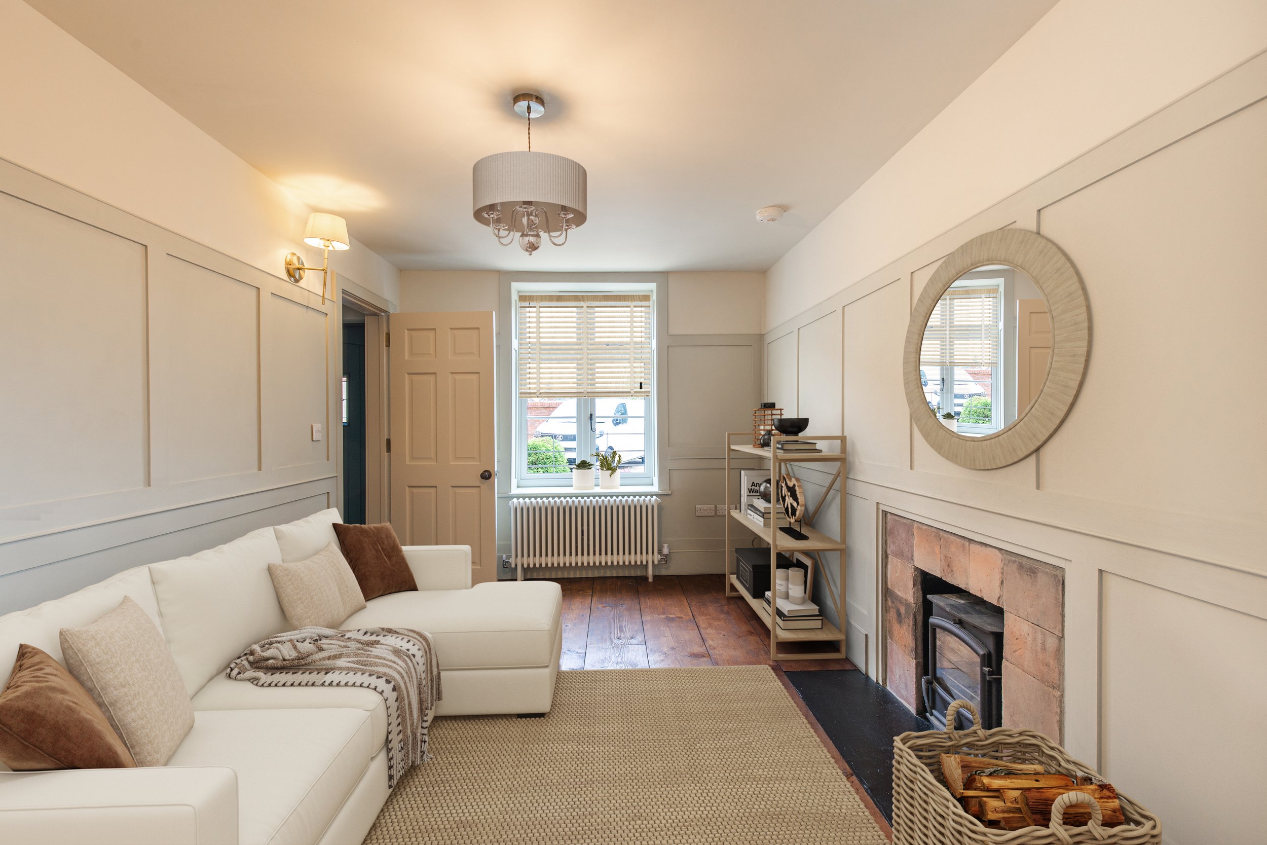 Living room with white sofa, beige pillows, a fireplace, bookshelf, and window with blinds
