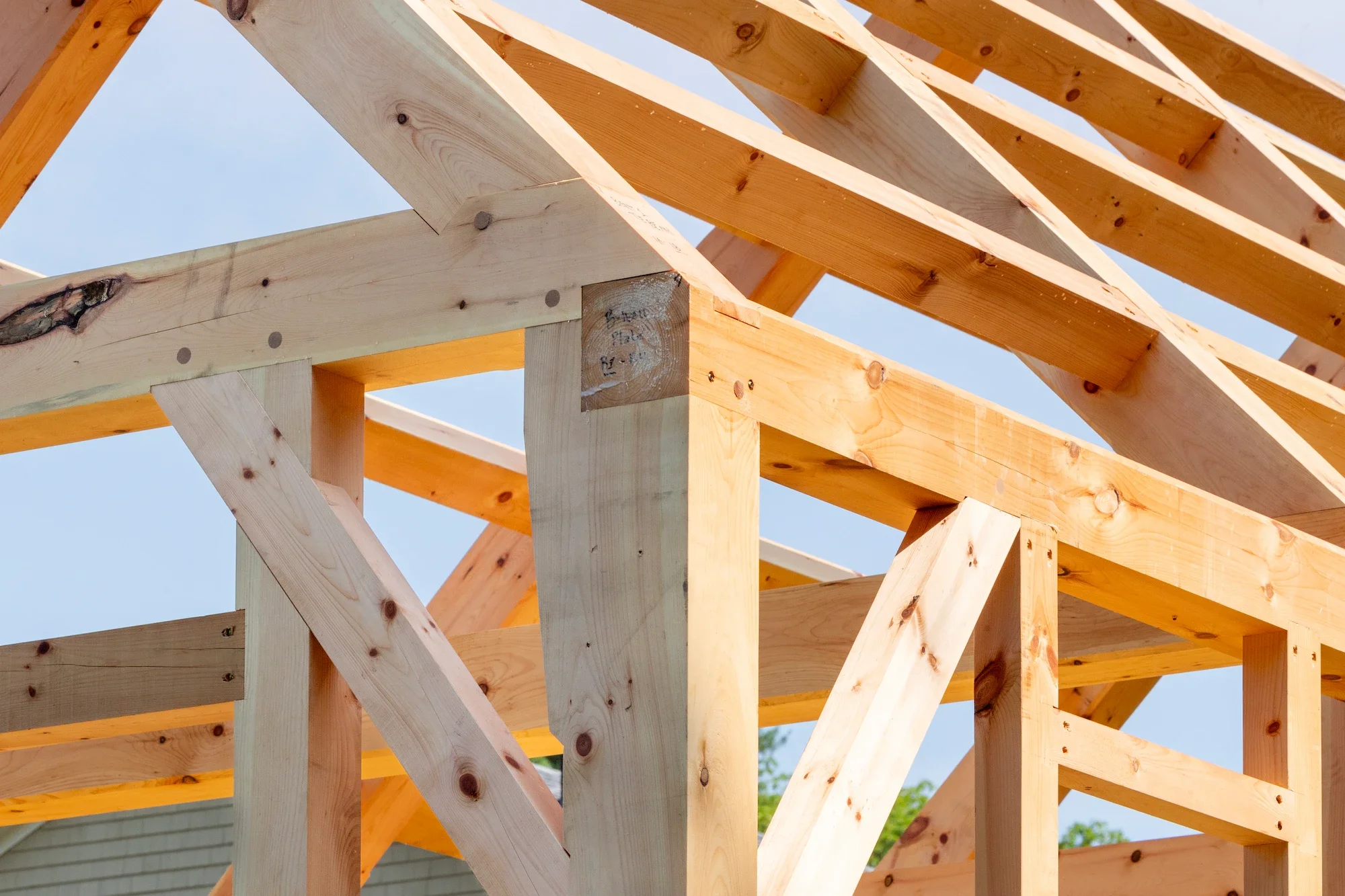 Wooden framing of a building under construction against a blue sky.