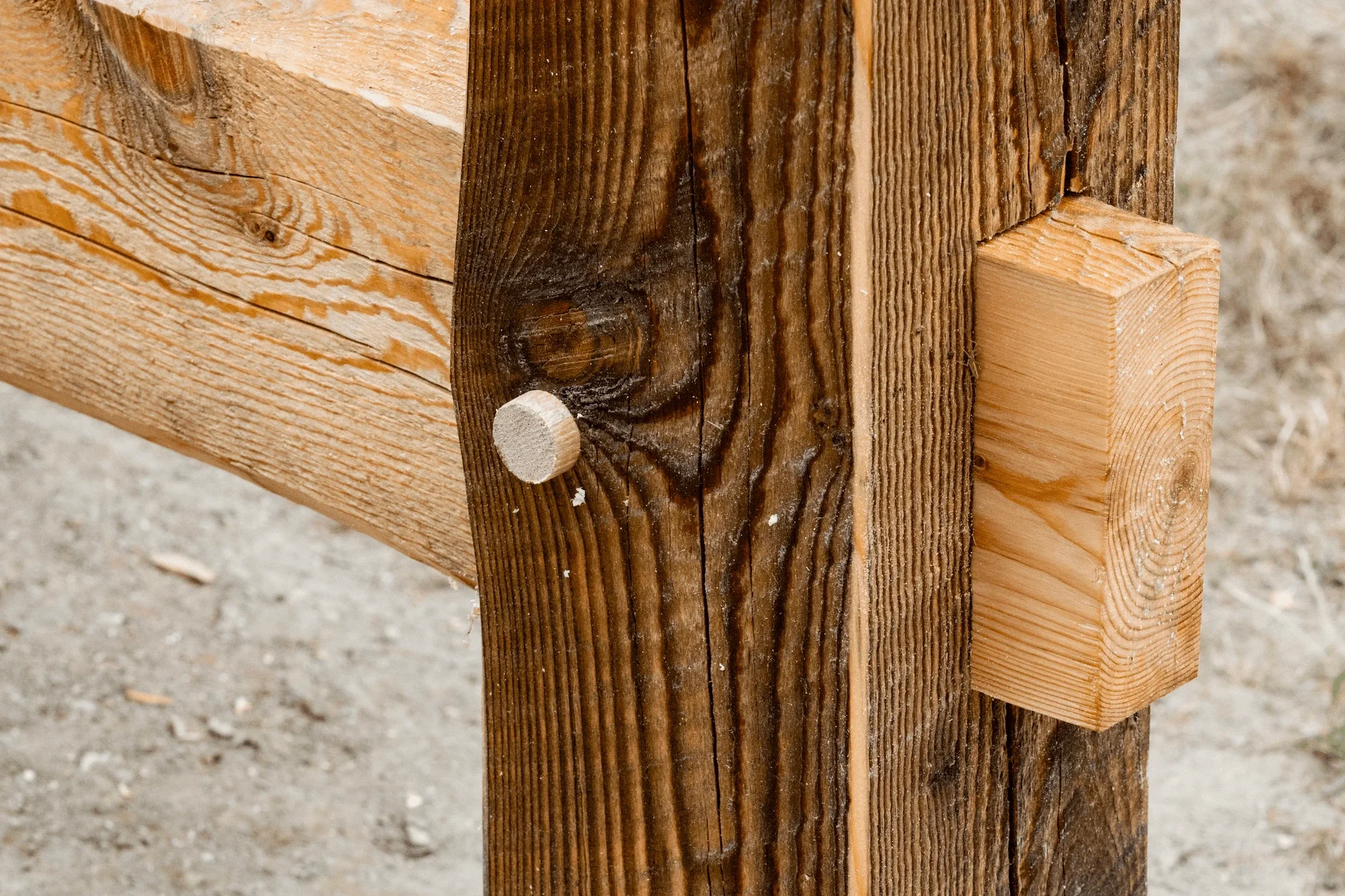 Close-up of a wooden structure with a vertical post and horizontal beams, showing the connection joint.