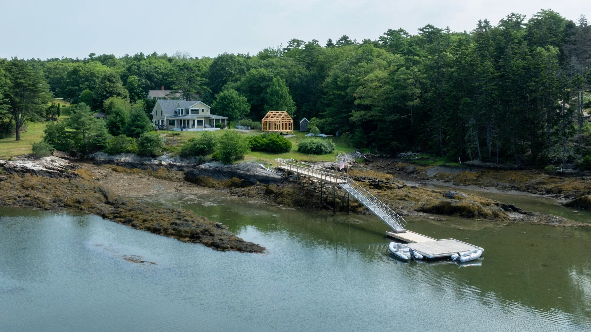 Lakeside house with a dock and boat, surrounded by lush green trees and hills.