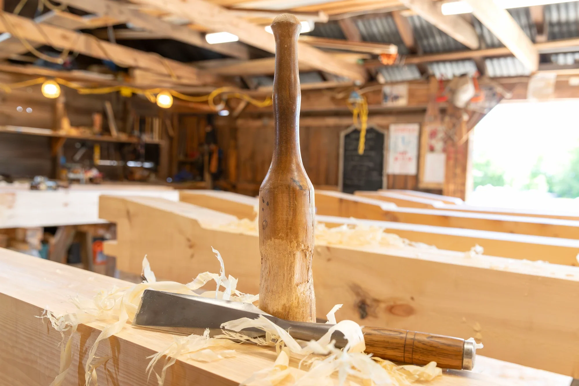 Close-up of a woodworking chisel and mallet on a wooden workbench in a carpentry workshop.