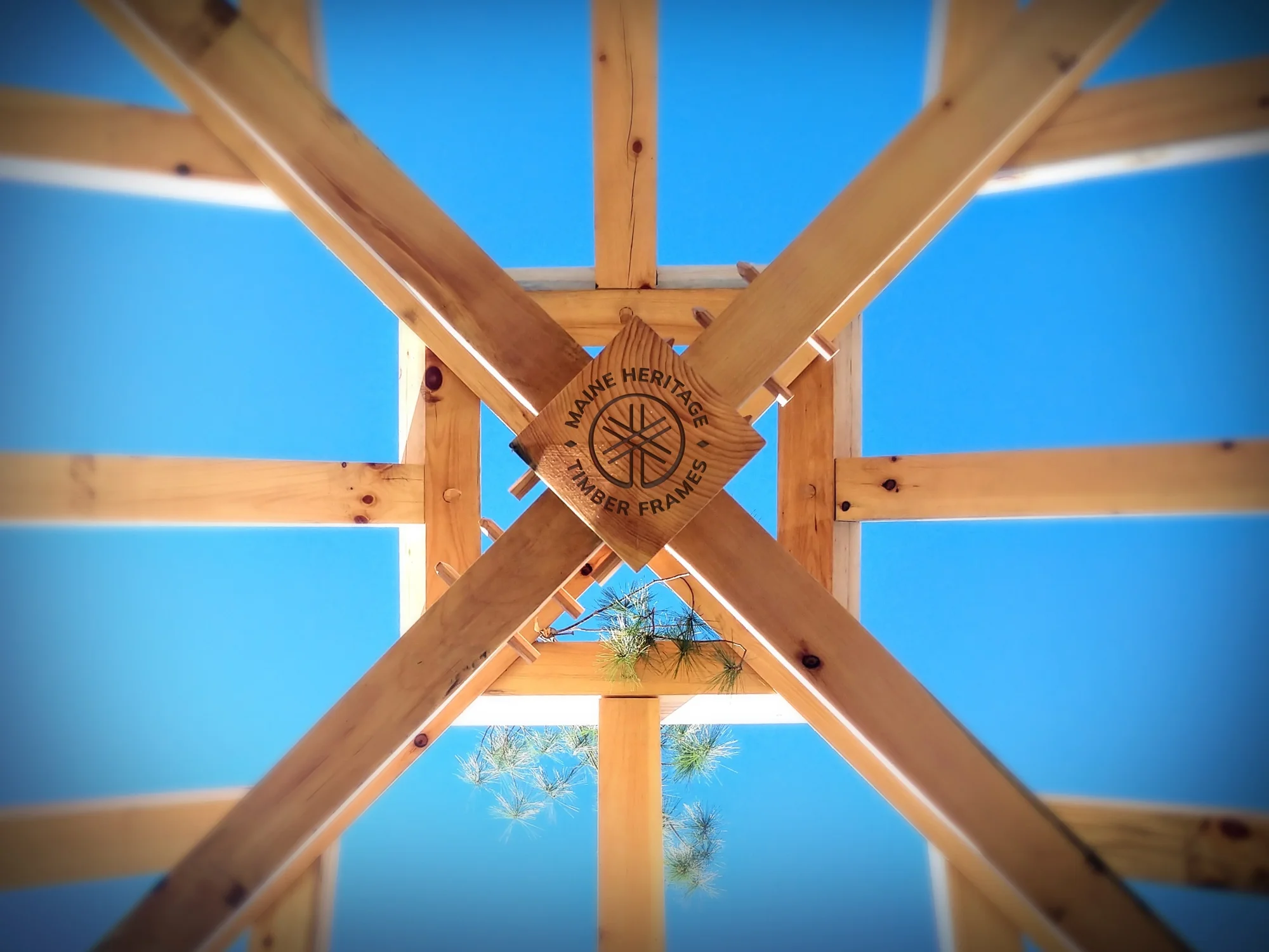Looking up at a wooden timber frame structure with a blue sky background.
