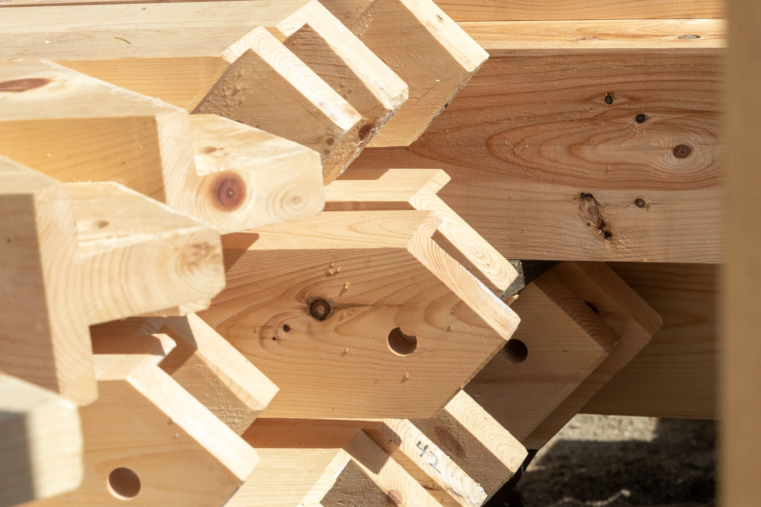 Close-up view of wooden structures with holes, arranged in a stack, likely components of furniture or construction wood.