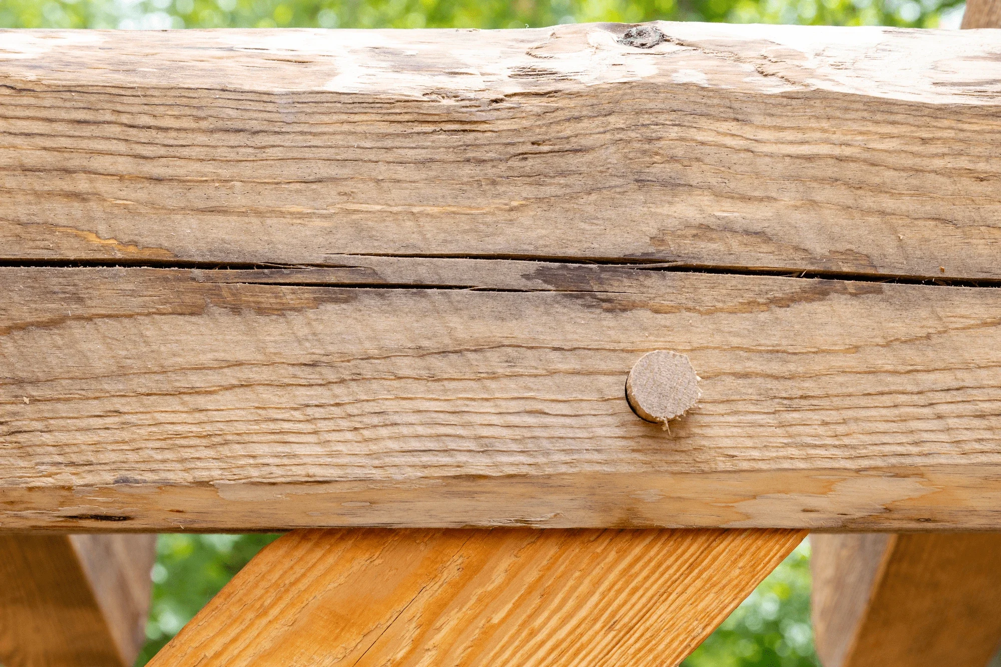 Close-up of a wooden beam fastened with a round wooden dowel, part of a wooden structure outdoors.