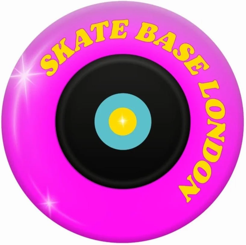 A pink and purple skateboarding wheel with the words 'SKATE BASE LONDON' written in yellow around the circumference, and a central black hub with a blue and yellow design resembling a vinyl record.