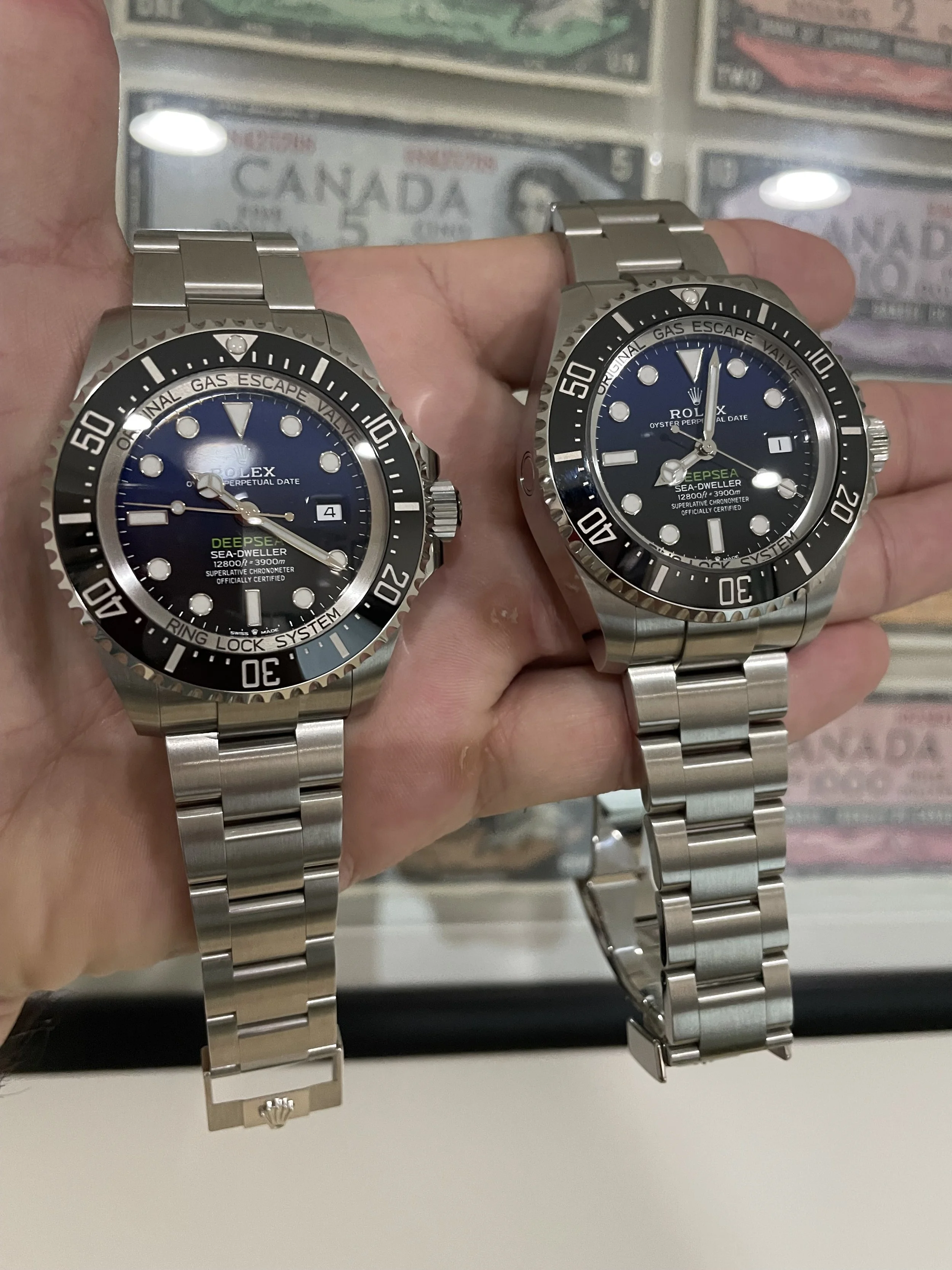 A person holding two Rolex Sea-Dweller Deepsea watches with black dials and metal bands, with a background of Canadian currency.