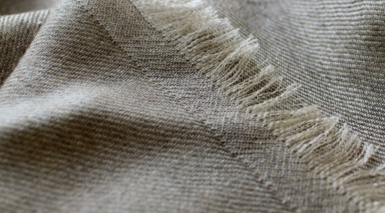 Close-up of beige woven fabric with frayed edges.
