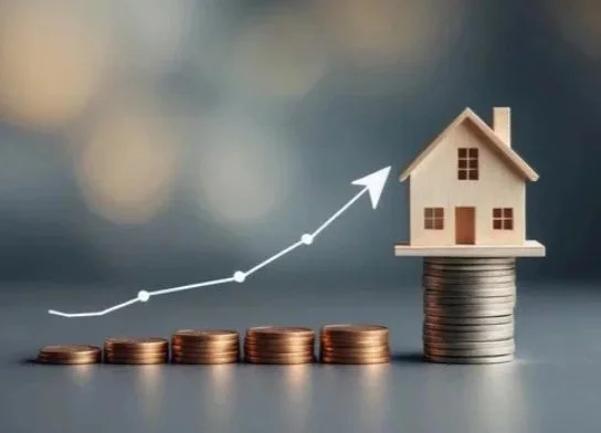 Stacks of coins with a small house on top and an upward trending line graph.