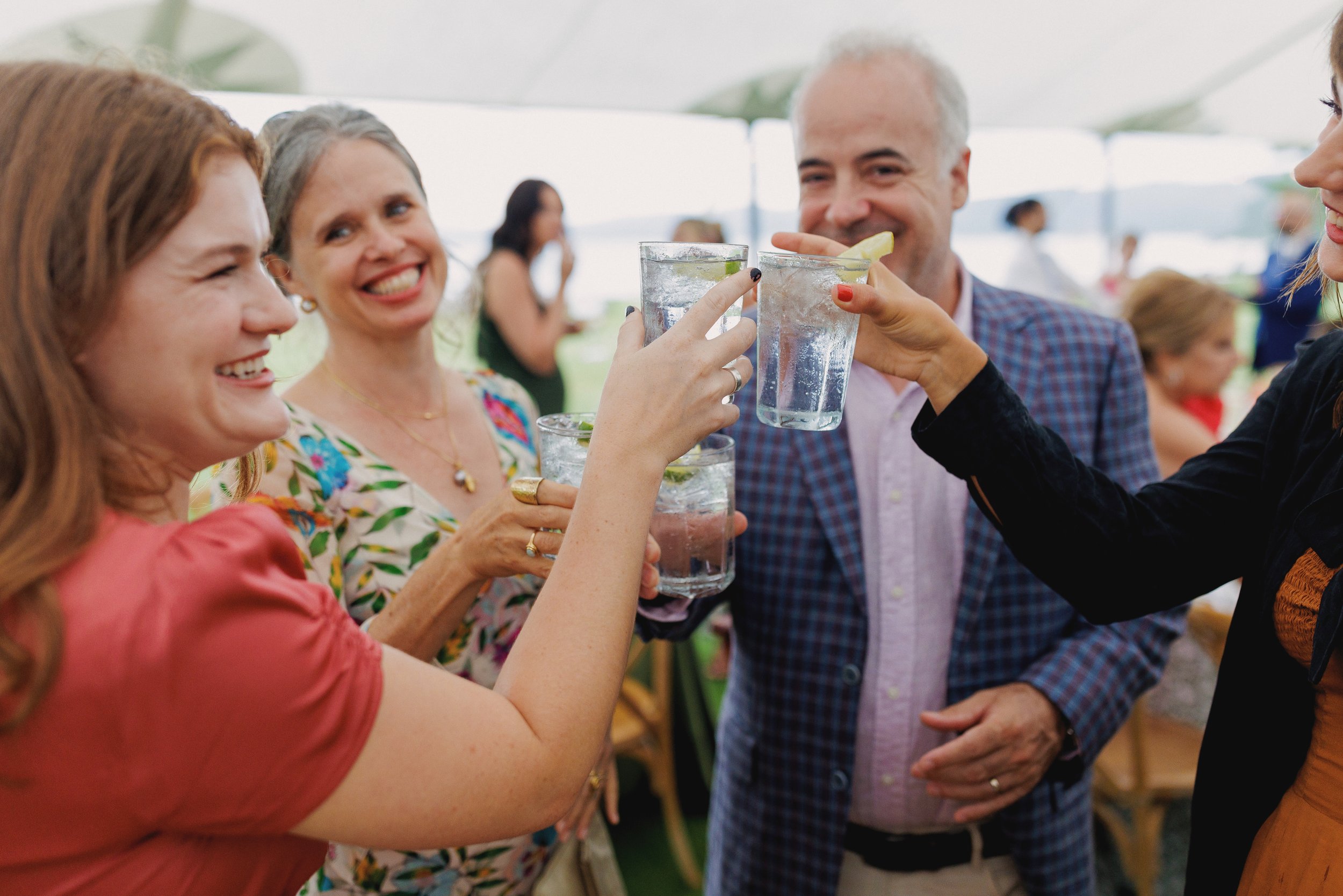 People at an outdoor gathering raising glasses of cocktails for a toast.