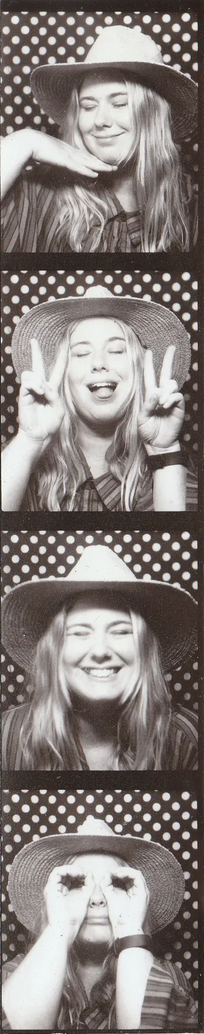 Four black-and-white photo booth images of a young woman wearing a wide-brimmed hat with a polka dot background. In the first, she smiles with her hand under her chin. In the second, she makes peace signs with both hands. In the third, she laughs with her eyes closed. In the fourth, she holds her hands up to her eyes as if framing them like glasses.