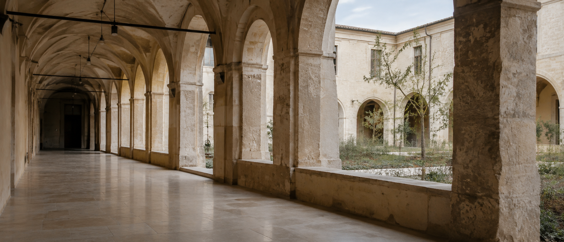 Claustro de piedra con arcos y jardín central bajo luz suave, un espacio elegante y sereno para bodas y eventos.