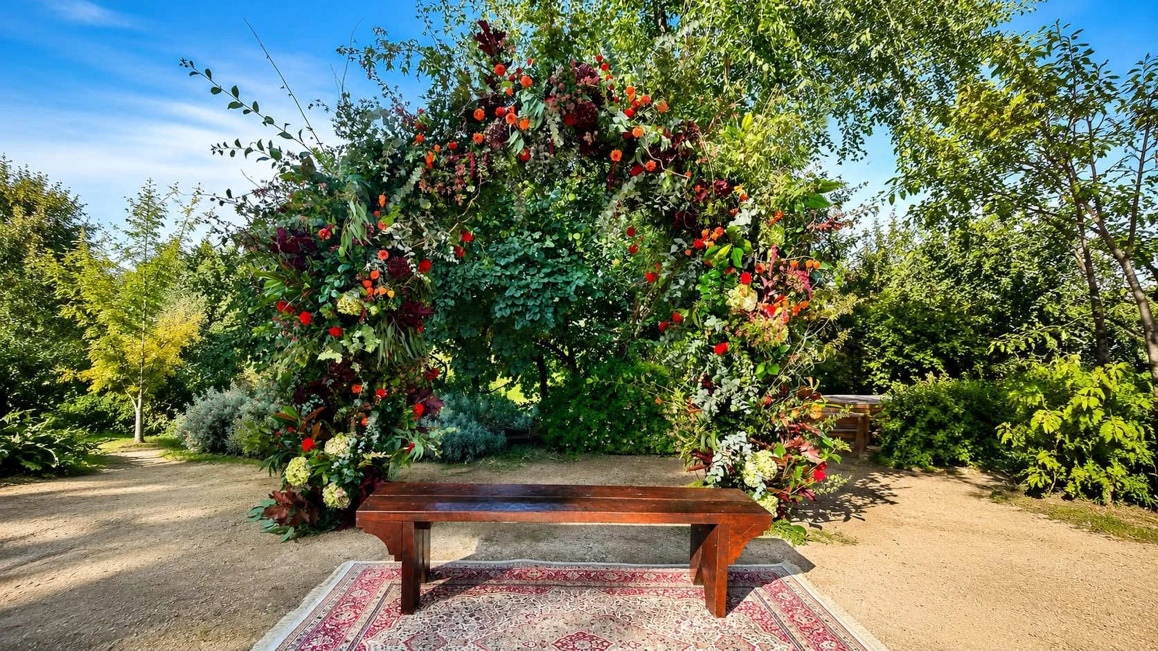 Arco floral para una ceremonia civil de boda en otoño y al aire libre, con banco de madera y alfombra entre árboles.