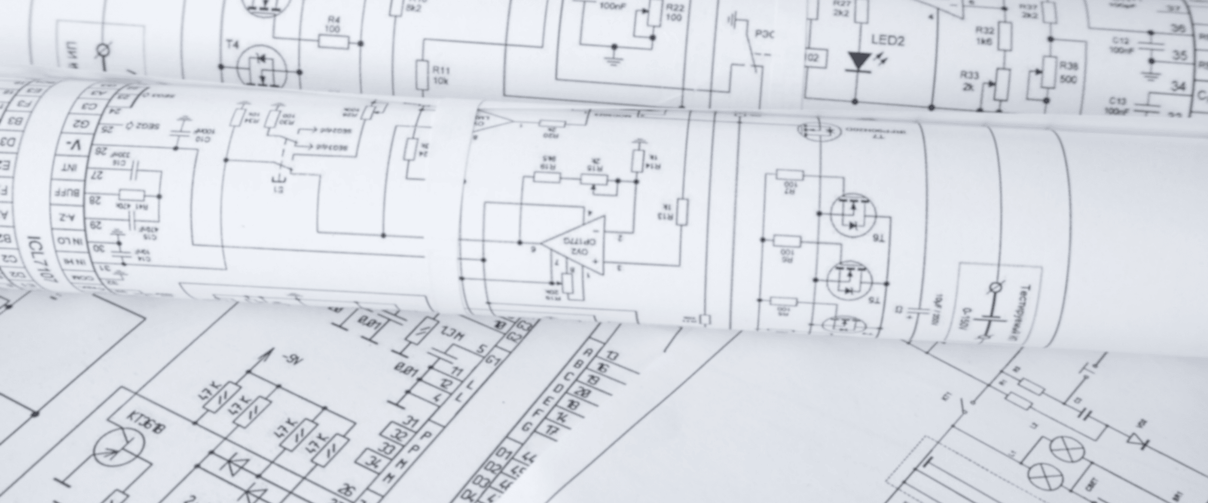 Close-up of electrical engineering blueprints and circuit diagrams printed on white paper, partially rolled up.