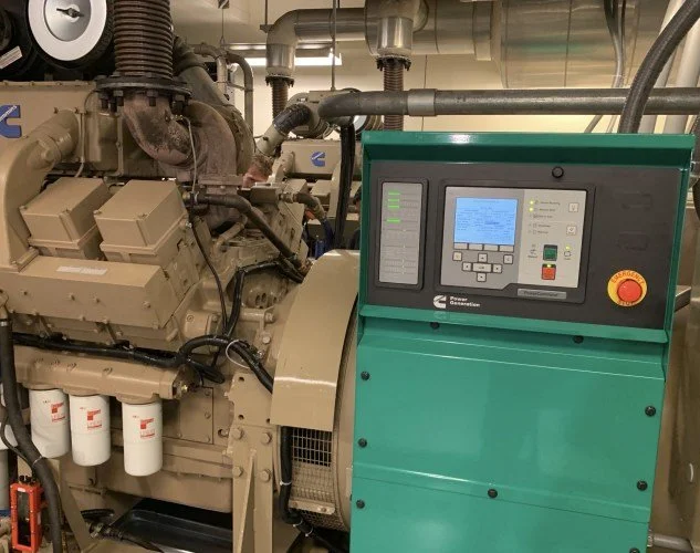 Industrial generator machine with control panel and fuel filters in a mechanical room.