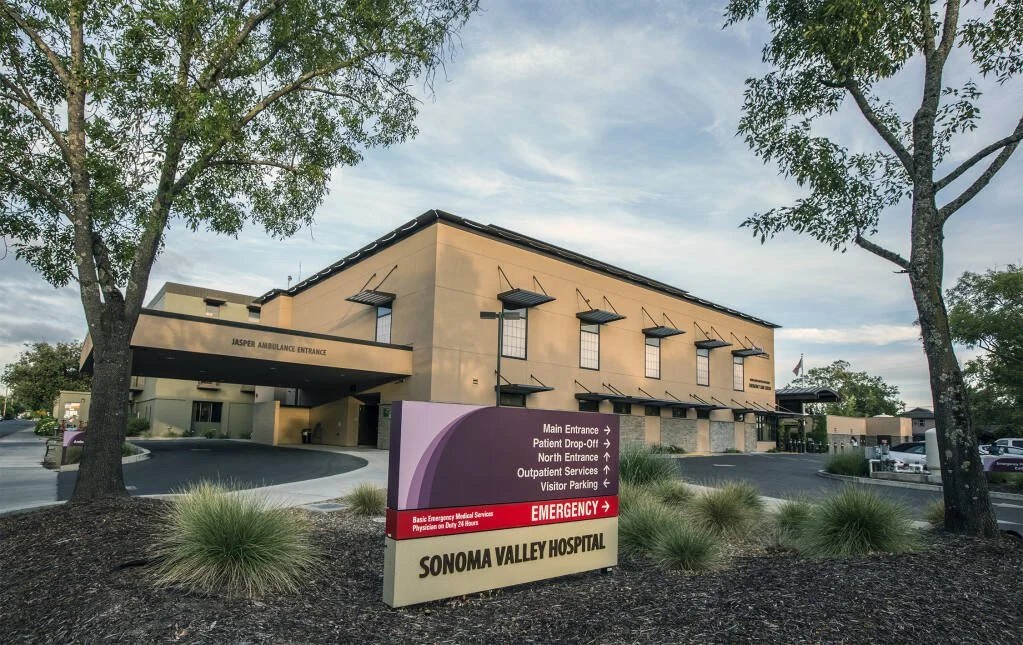 Exterior of Sonoma Valley Hospital with an emergency and visitor directional sign in the foreground.