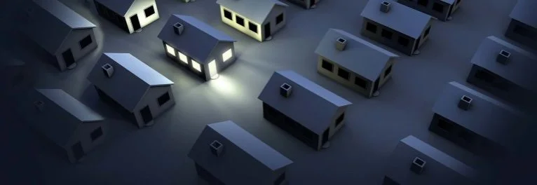 A bunch of houses in the dark, and one single house with power on.
