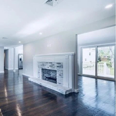An empty modern living room with a white fireplace and sliding glass doors leading outside. Built Structure Pro in Massachusetts