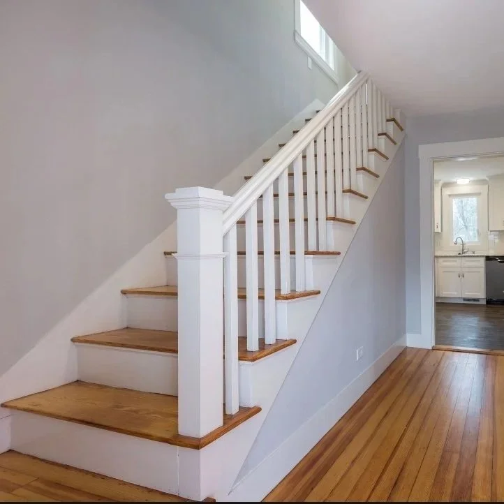 Wooden staircase with white risers and railings in a bright home interior. Built Structure Pro in Massachusetts