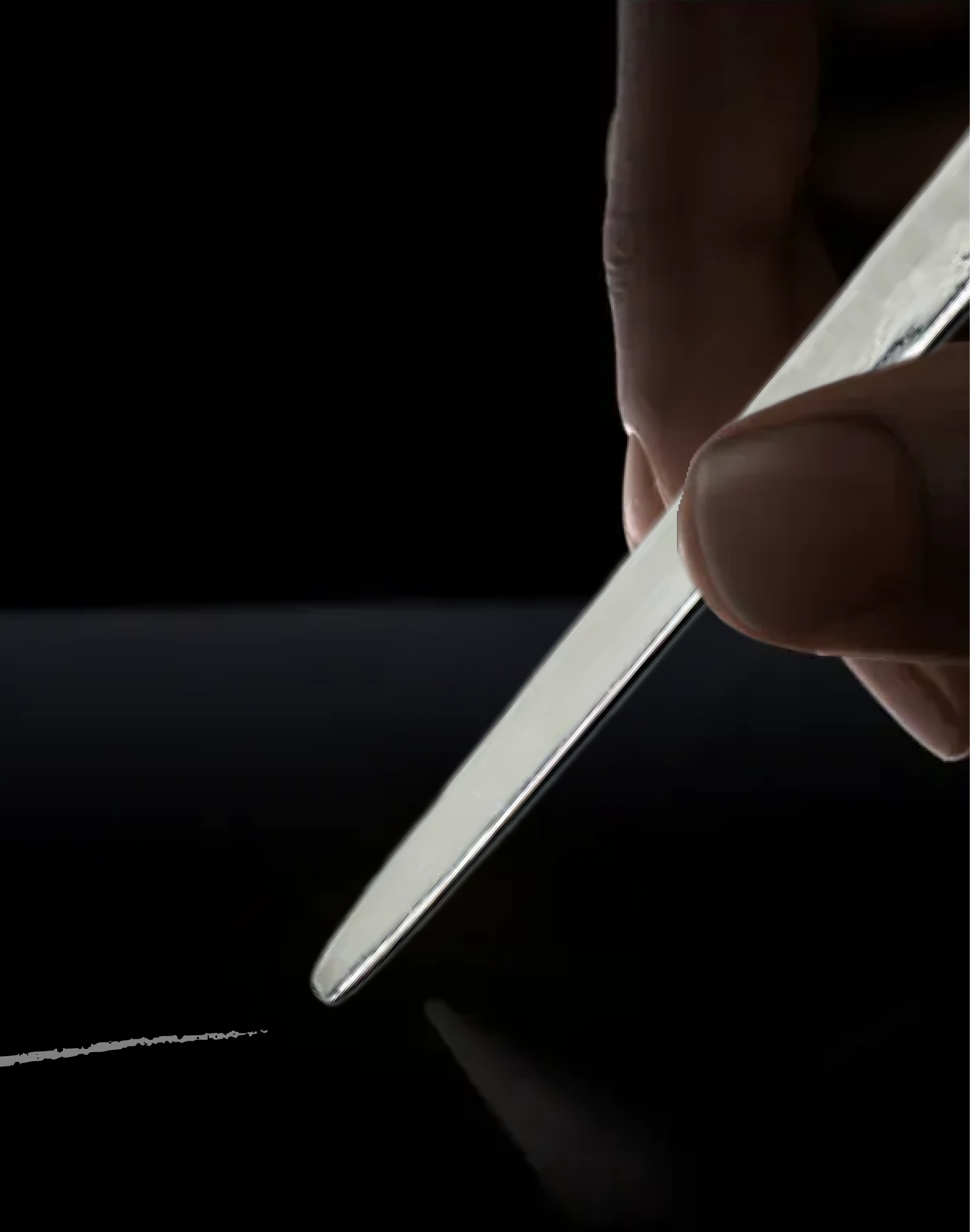 Close-up of a person's hand writing on a black surface with a Silver Pencil