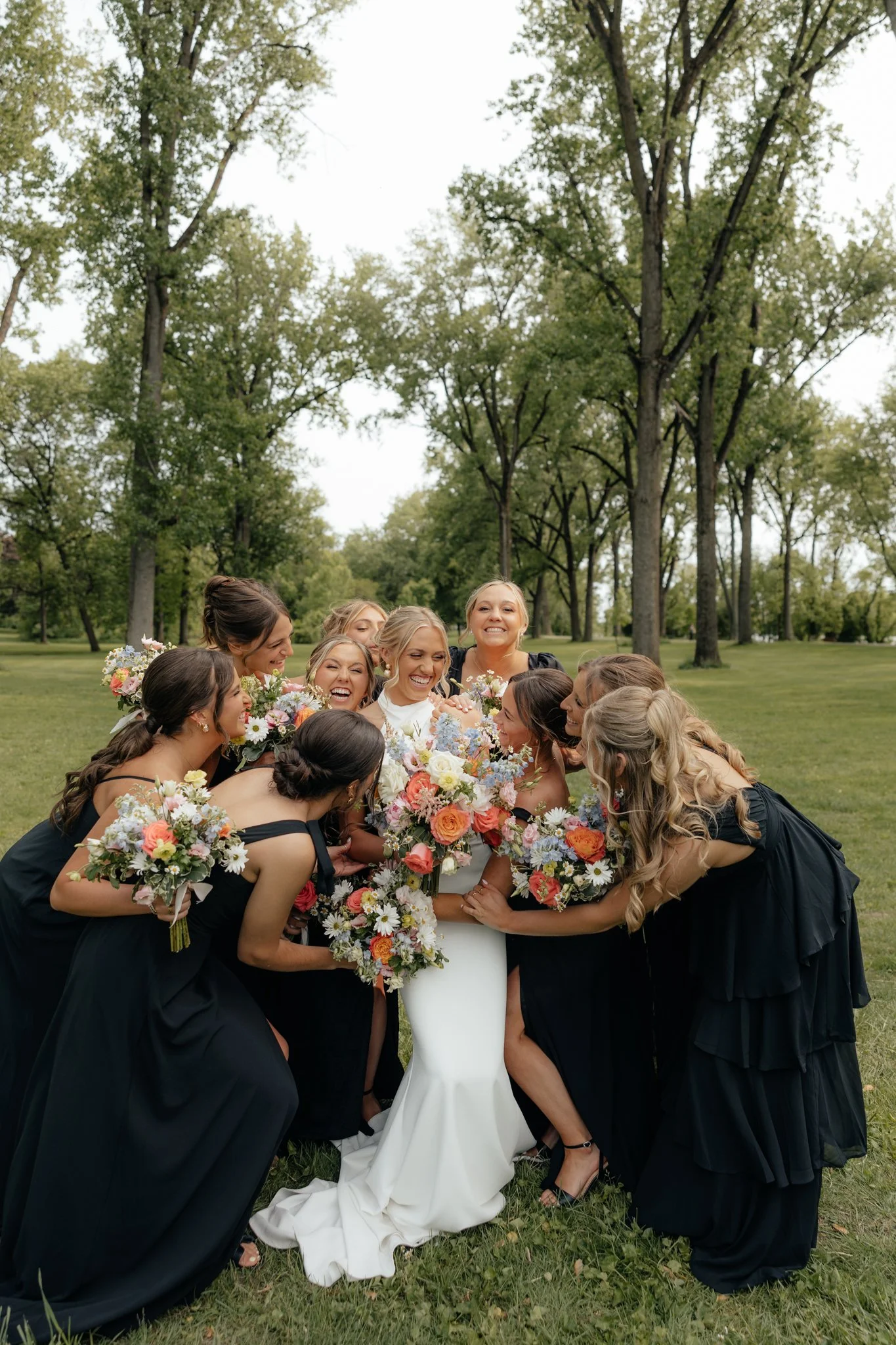 Bridal party photos celebrating bride on wedding day in Grand Rapids, Michigan at The Broadway Avenue and Riverside Park, candid and giggly.