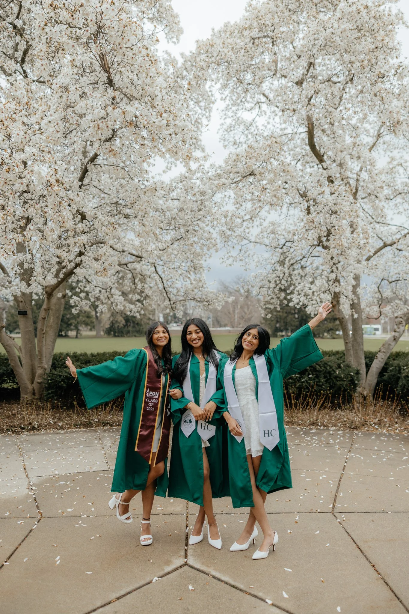 Friend group of Michigan State graduates celebrating graduation in the spring, champagne pop with MSU gown.