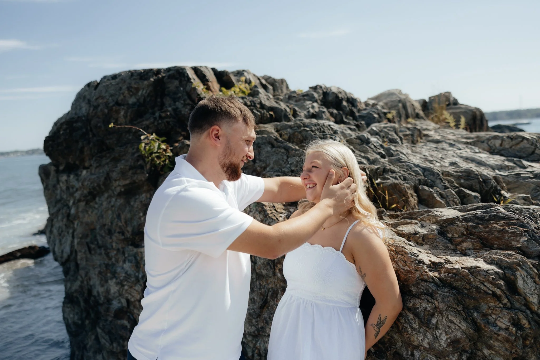 Couples session at rocky and sandy beach off the coast of Portland, Maine with sailboats and engagement photos on east coast.
