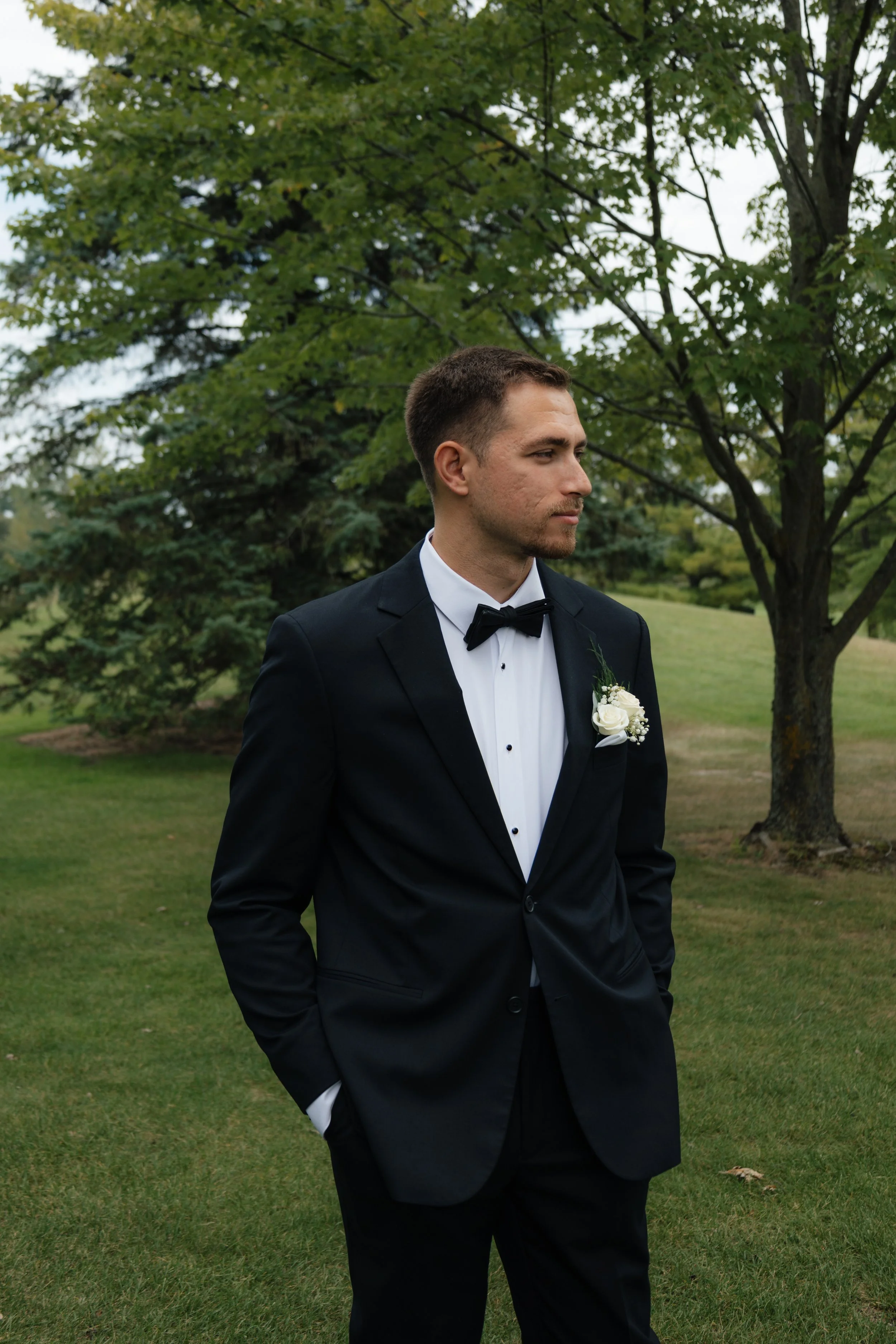 Groom in bridal tuxedo wearing corsage at Grand Rapids venue, bow tie wedding inspiration, classic wedding look.