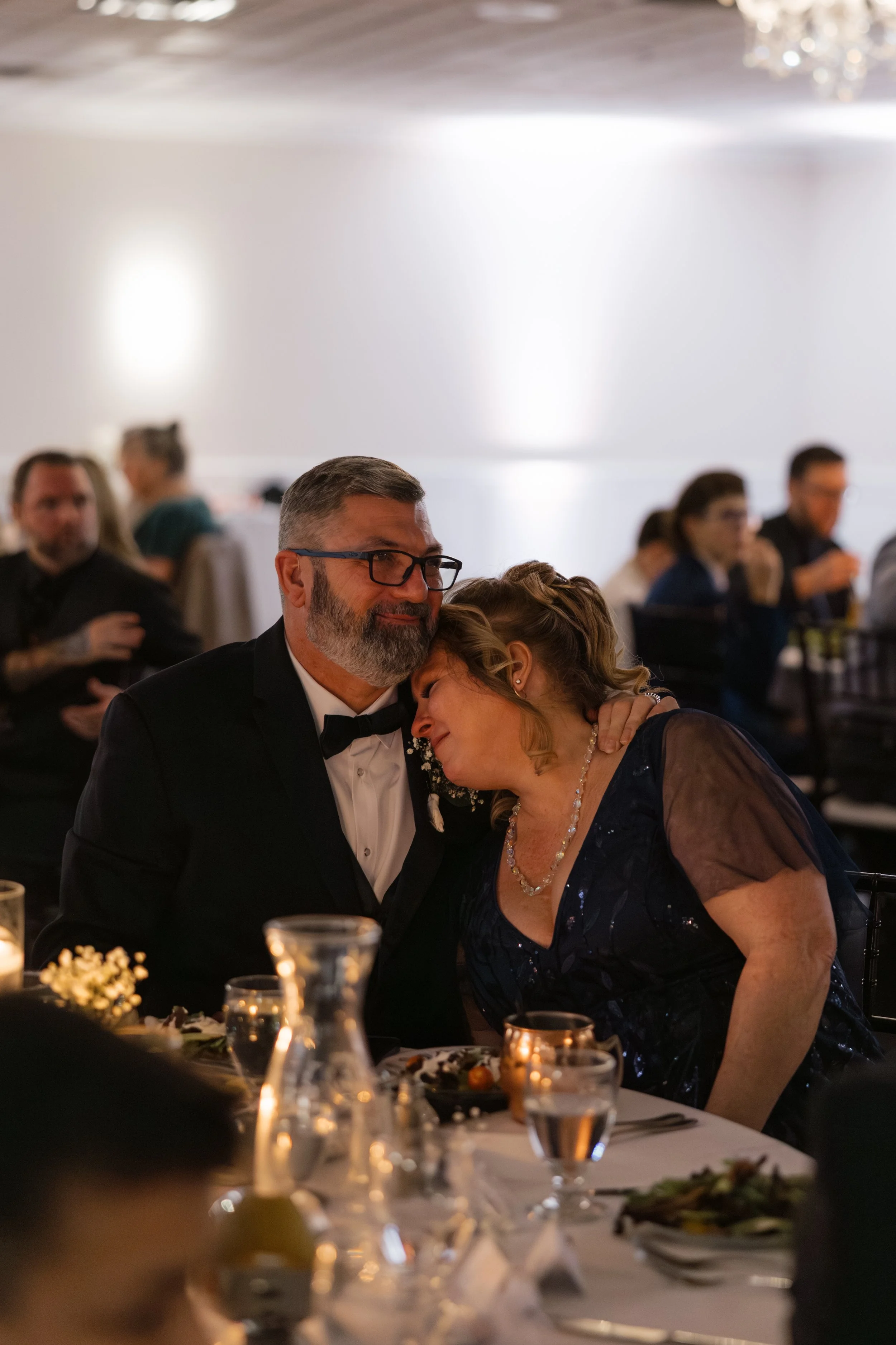 Emotional candid documentary moment with brides parents at wedding reception in West Michigan venue.